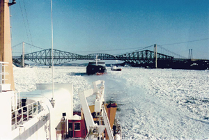 Photo 3.2: An icebreaker escorting a freighter above the Québec City bridges clearly show thick river brash ice.